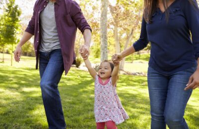 Mixed race couple lifting young daughter in park, crop shot