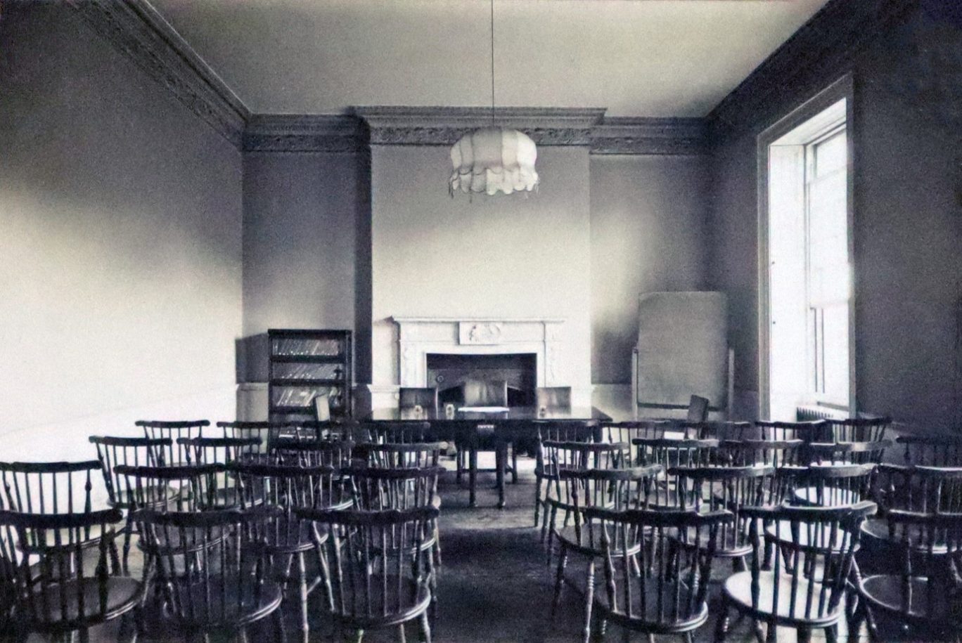Historical black and white image of chairs arranged for a lecture