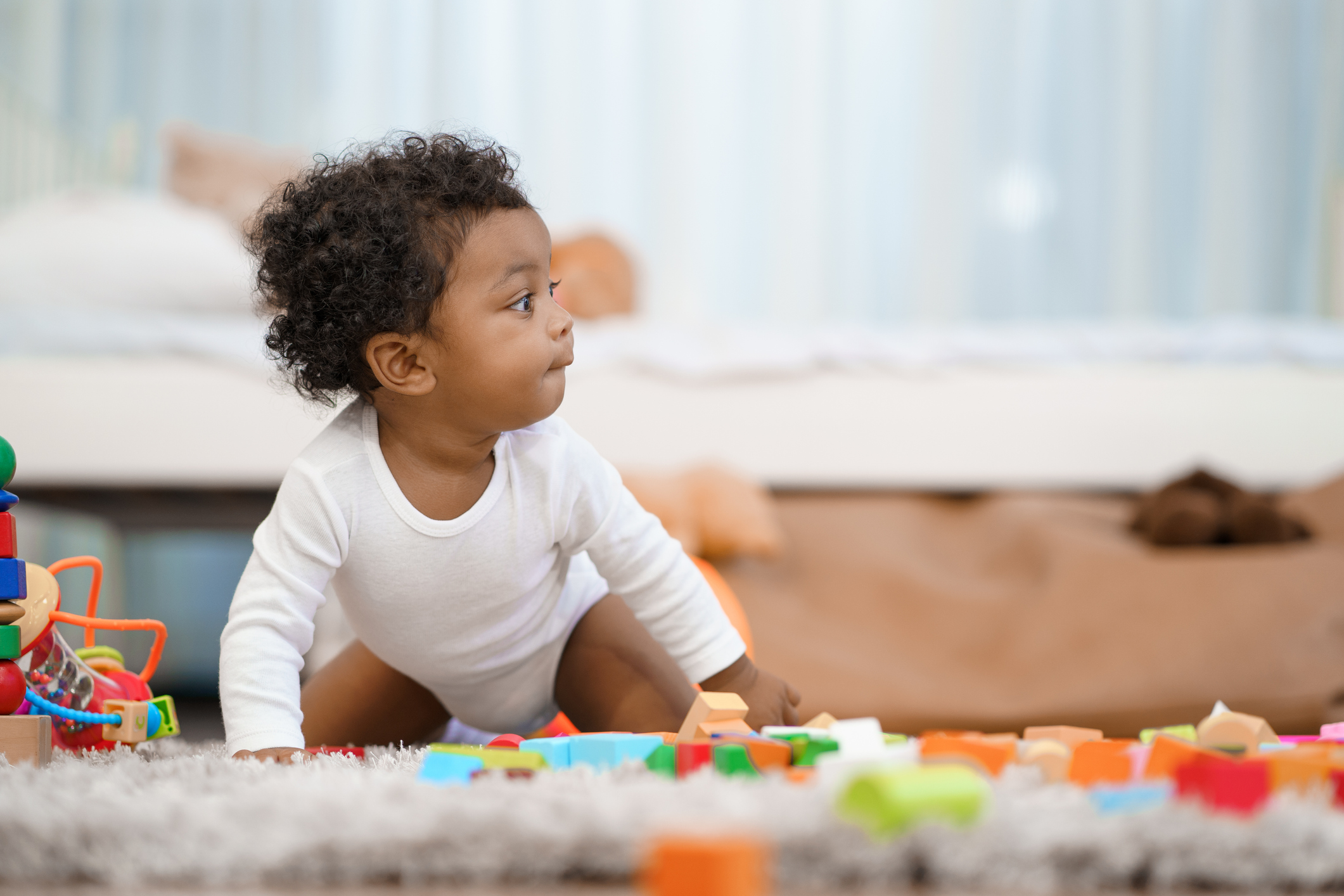Infant crawling amongst toys in bedroom