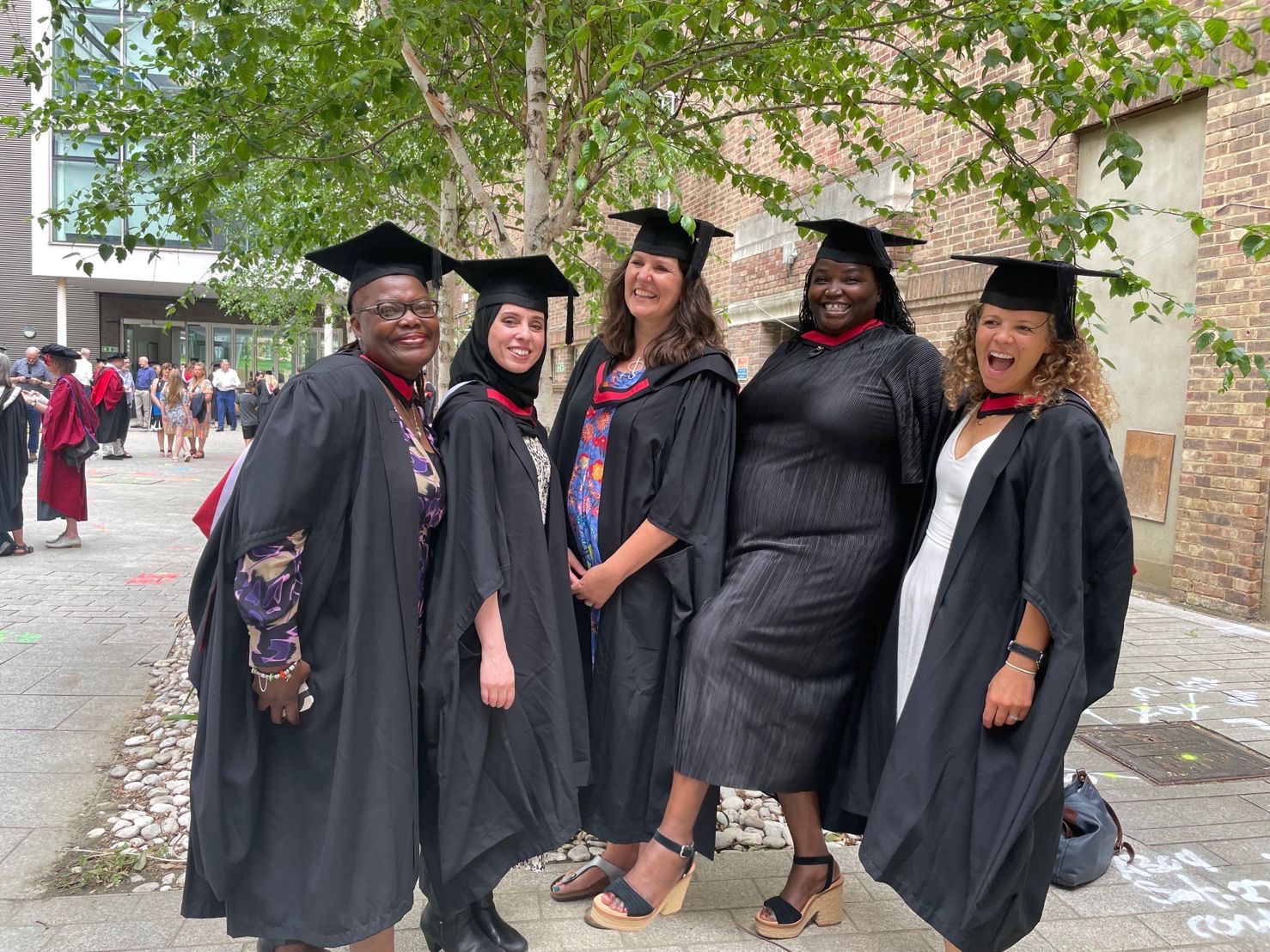 A diverse group of women graduates outside a university building. 