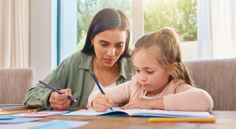 A woman supporting a young child with homework