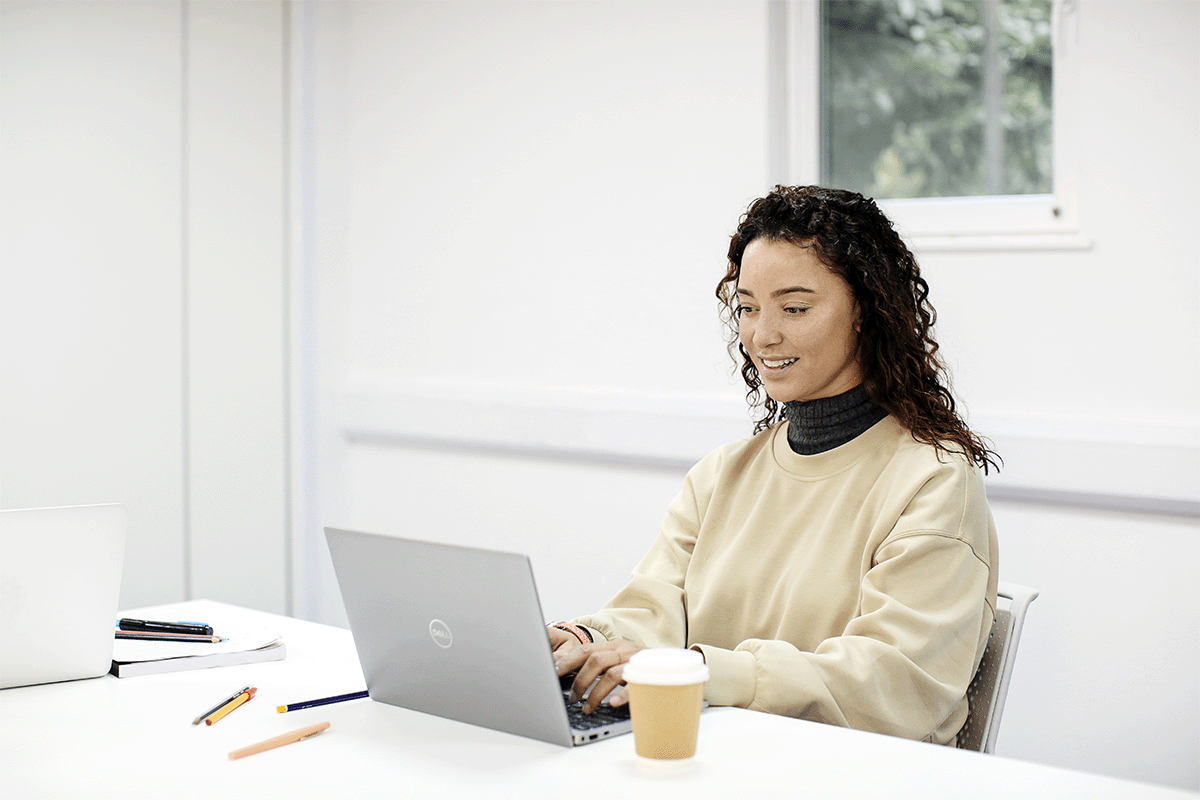 Student working at a desk on a silver MacBook. 