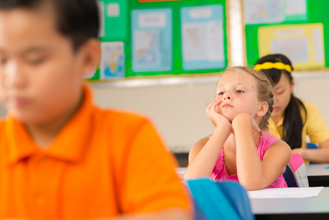 A young student looking bored in the classroom.