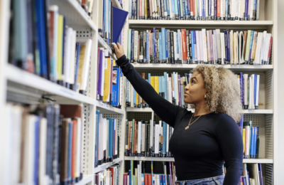 Student reaching for library book