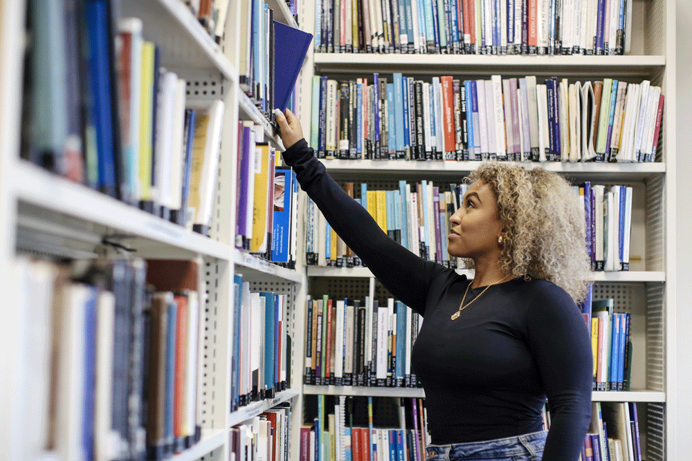 Student reaching for library book