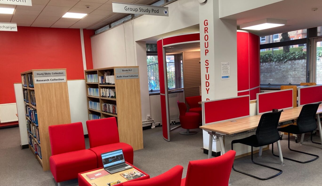 The rear end of a library space with a semi-enclosed area labelled 'Group Study Pod' and a collection of comfortable chairs with book shelves behind them. 