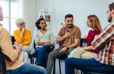 People sitting in a circle, having a group mental health therapy.