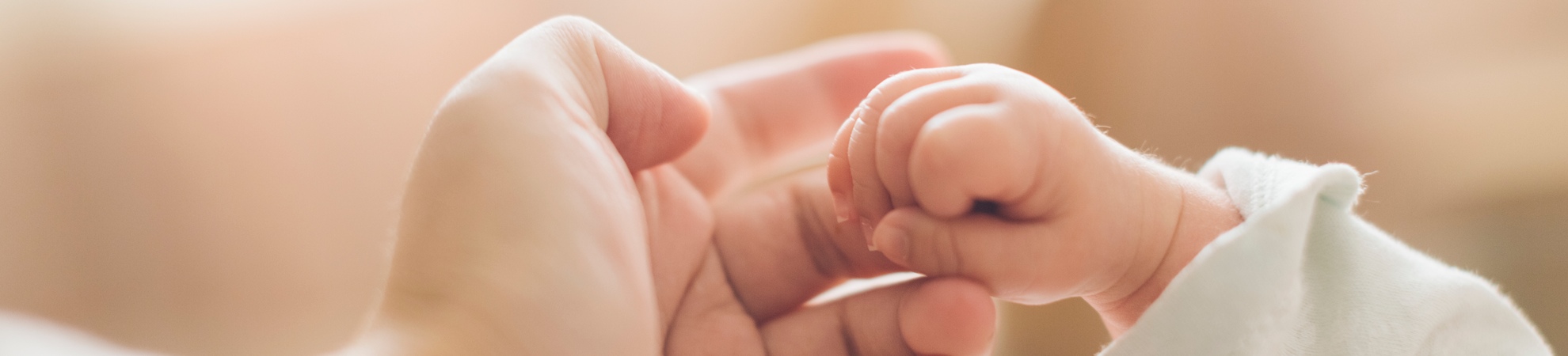 A baby holding an adults finger
