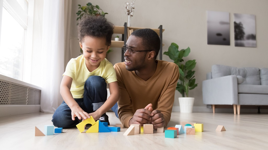 A father and daughter sat on the floor playing with toys.