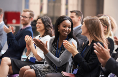 Audience smile and applaud at conference.