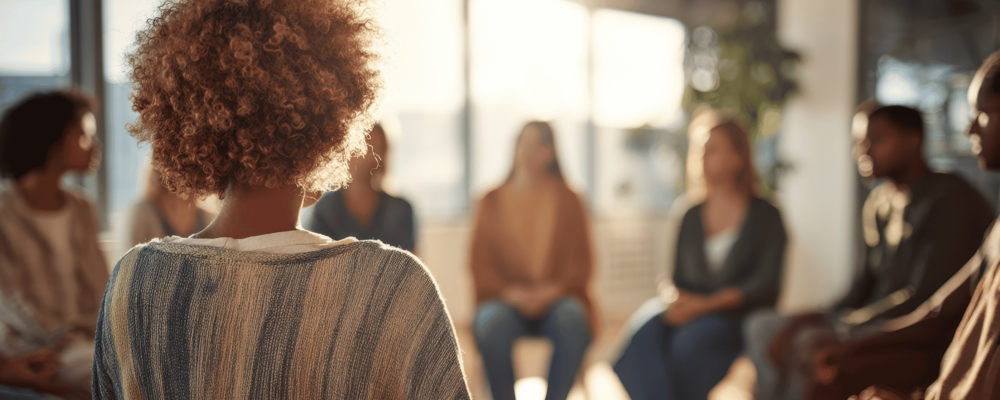 Back of a woman's head, part of a circle of people.
